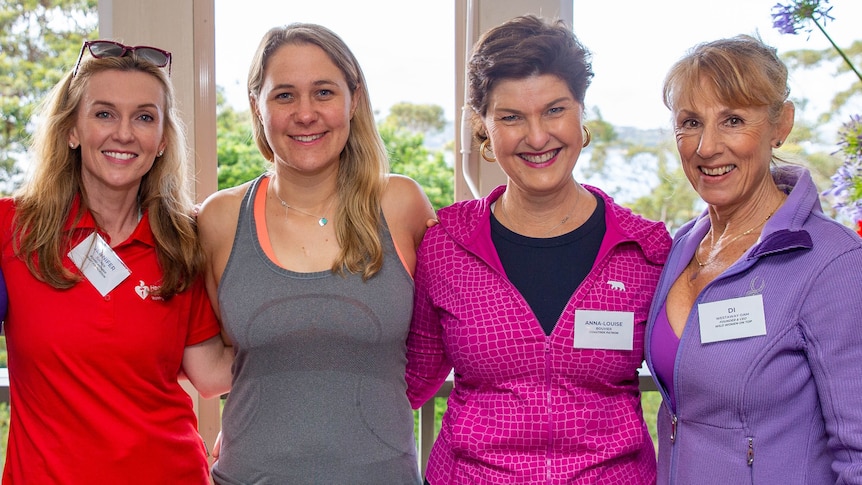 Four women smiling at the camera in various activewear