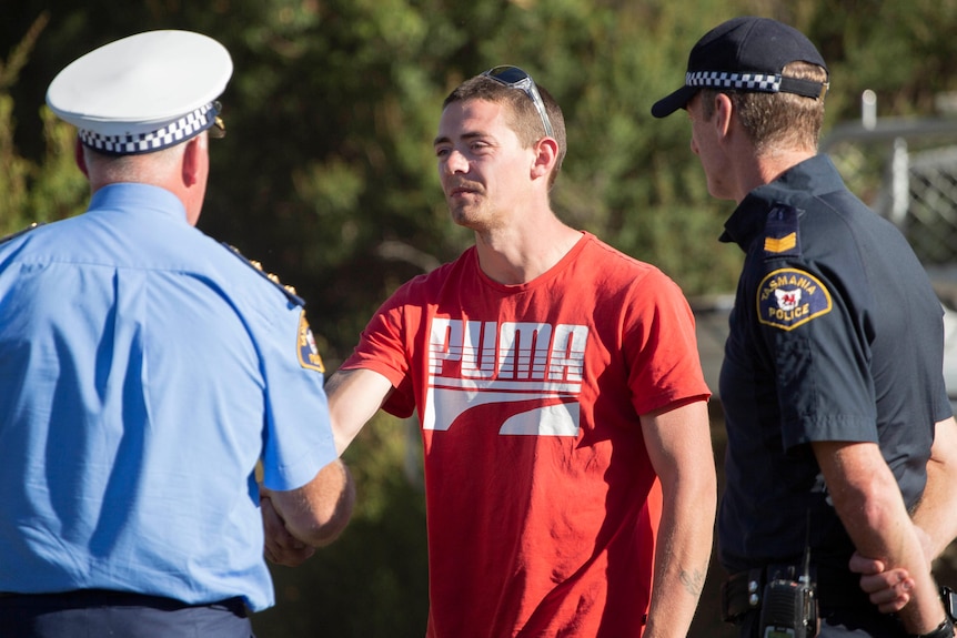 A man in an orange shirt shakes the hand of a policeman