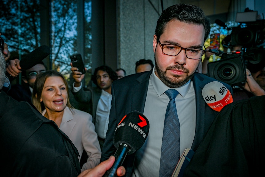 Bruce Lehrmann leaves Federal Court in Sydney, surrounded by people, looking serious