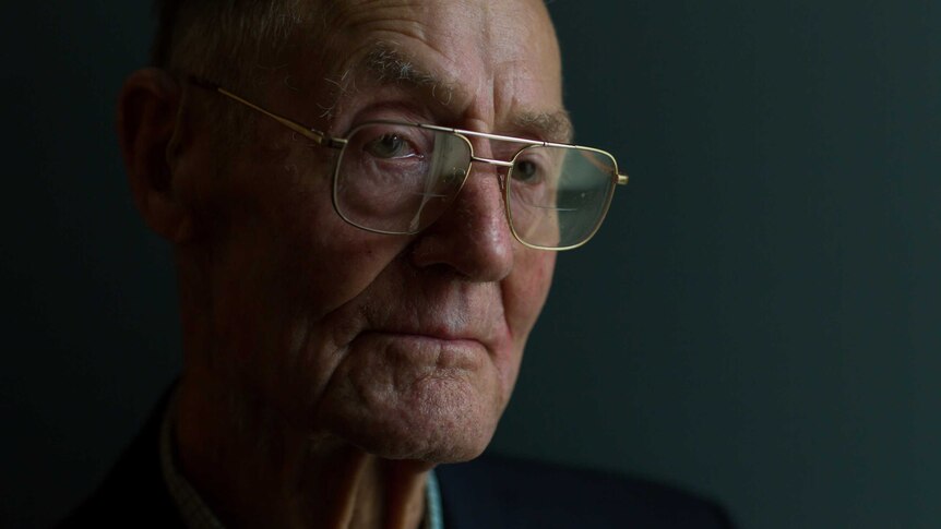 World War II veteran Andy Bishop has glasses on his nose and a tear in his eye as he poses for a portrait.
