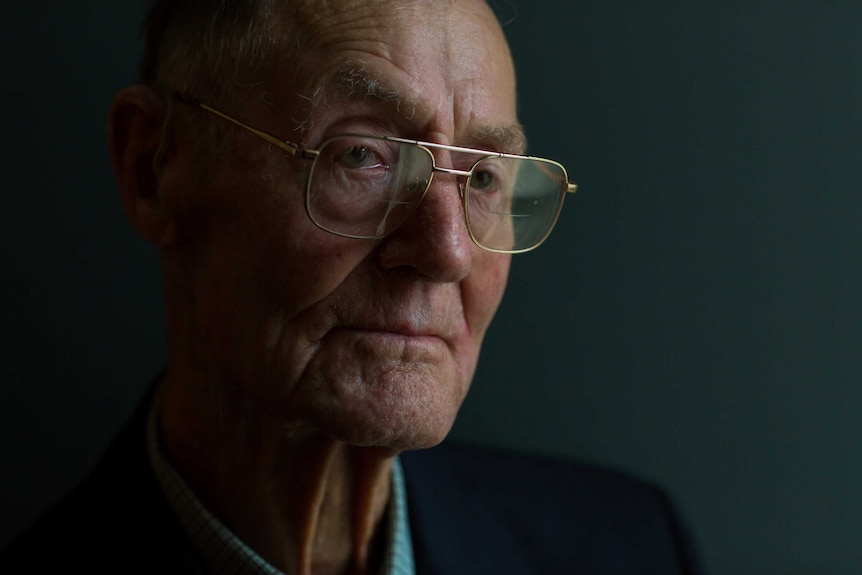 World War II veteran Andy Bishop has glasses on his nose and a tear in his eye as he poses for a portrait.