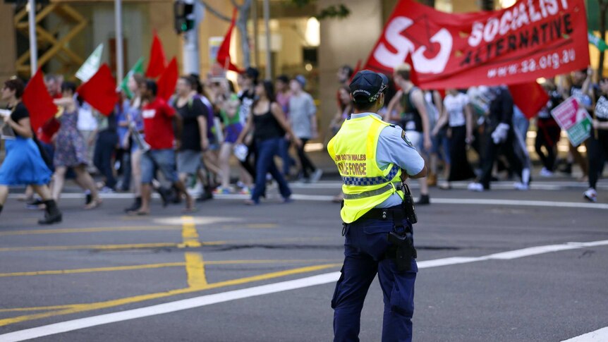 A police officer watches marchers during a rally supporting marriage equality.
