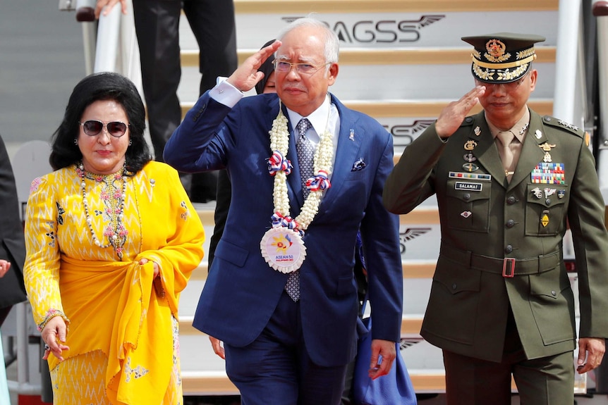 Najib Razak salutes the honour guards, next Rosmah Mansor, upon arrival in the Philippines for the 2017 ASEAN Summit.