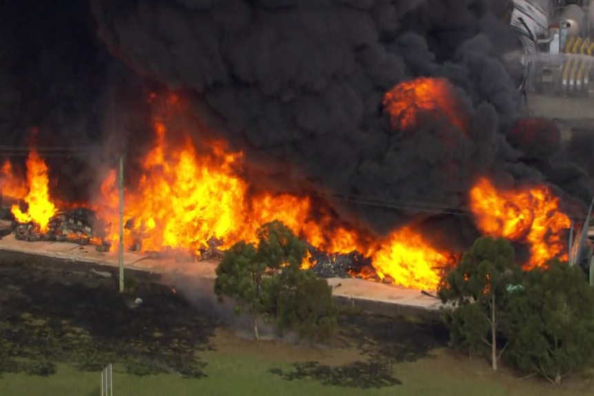 A factory is engulfed in range flames and black smoke.