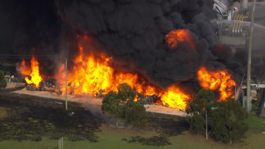 A factory is engulfed in range flames and black smoke.