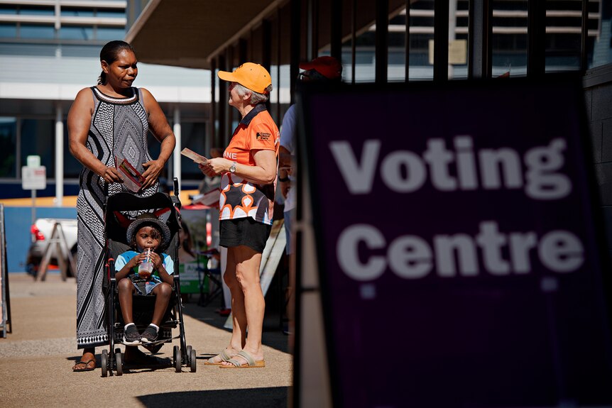 A woman pushing a stroller arrives at a voting booth to cast her vote.