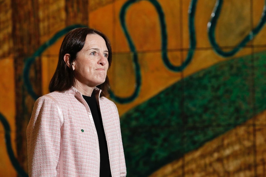 Celia Hammond looks into the distance in front of a mural