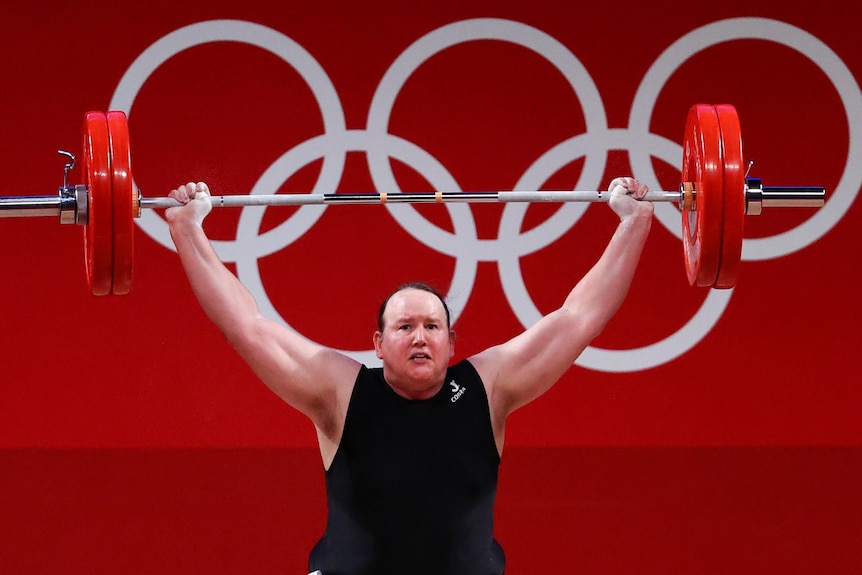Weightlifter Laurel Hubbard holds a weights above her head dressed in a black singlet