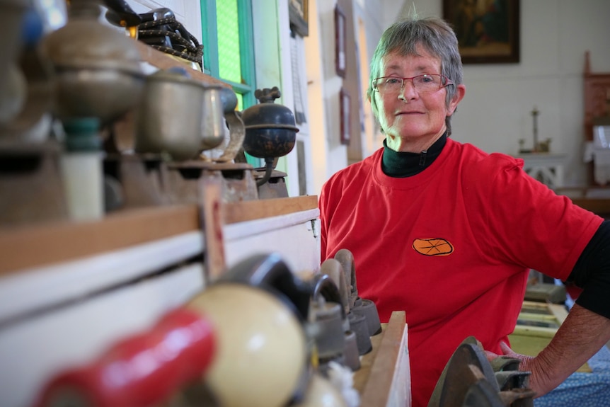 A woman with a red shirt and short hair stands next to a museum's display.