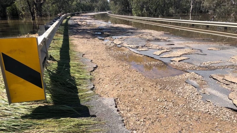 A road pavement on a bridge that has been significantly damaged by rain and flooding.