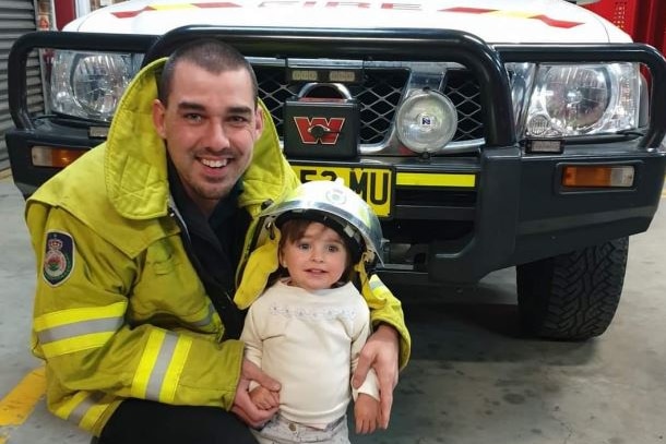 A firefighter with a young girl. 
