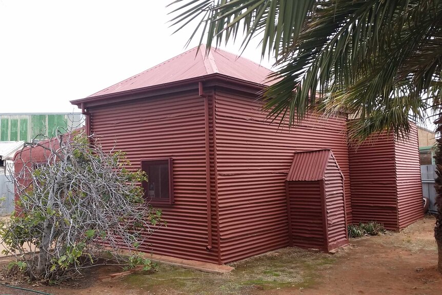 A photo of the side of the historic Broken Hill mosque, a maroon-coloured tin shed.