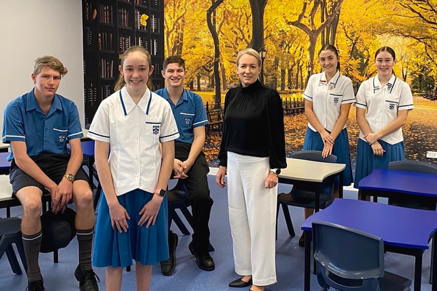 A school teacher standing with a group of students in a classroom