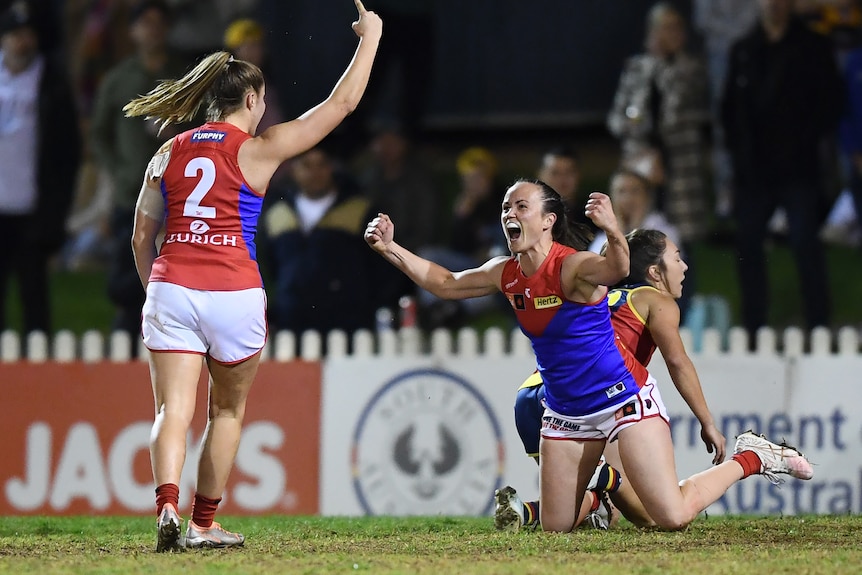Daisy Pearce pumps her fists while on her knees as a teammate runs to celebrate with her