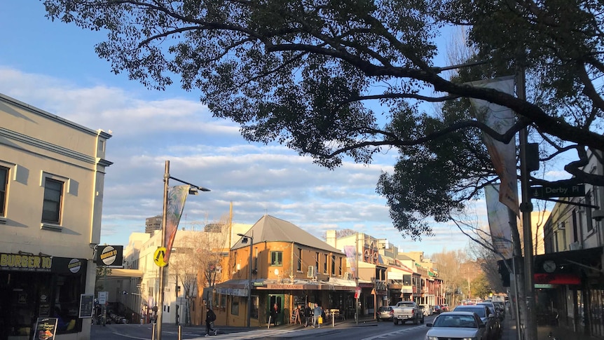 A view of shops and cars travelling along a Sydney street