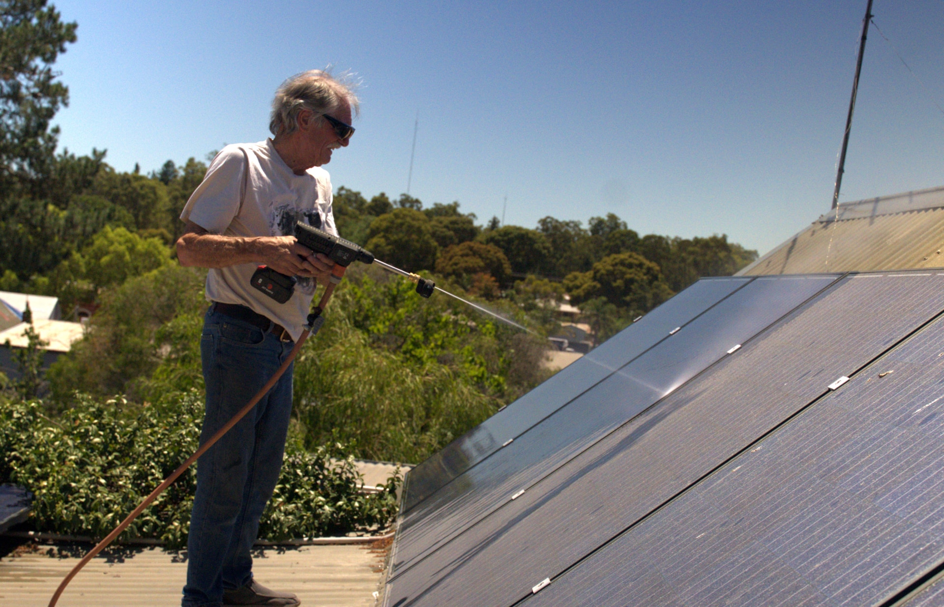 A pressão de Rick Fryer limpa seus painéis solares empoeirados.