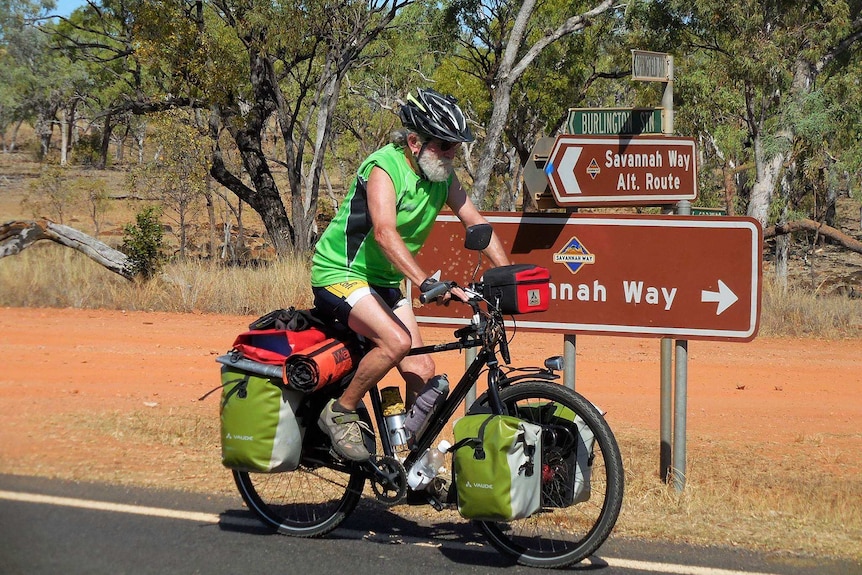 Older man on packed up bicycle riding past Savannah Way sign.