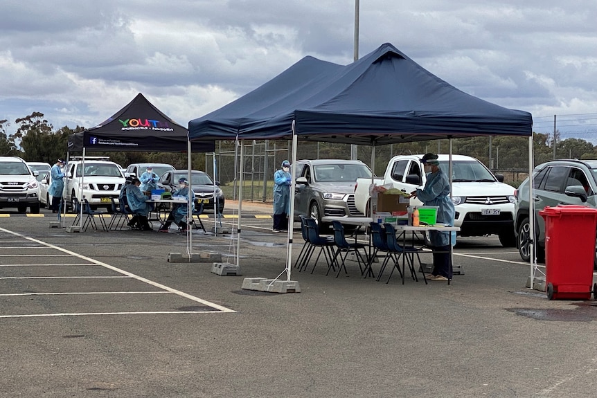 A group of people in protective clothing swab people in their vehicles