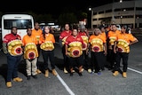 A group of Arrernte patrollers stand in a carpark at night-time