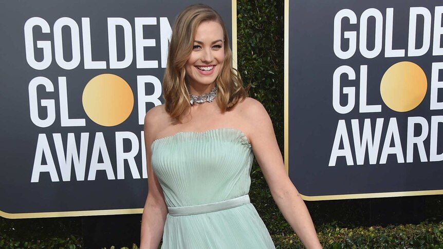 Yvonne Strahovski wearing a mint-green floor-length gown, holding a Time's Up ribbon