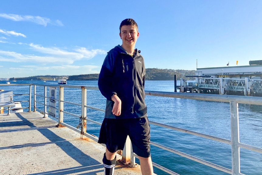 Matthieu Piggott smiling broadly as he walks down along the water.