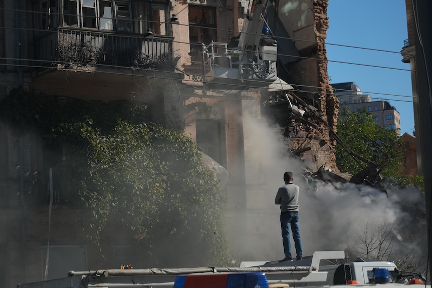 A civilian surveys the damage after a drone strike in Kyiv.