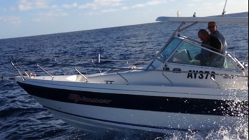 Motor boat being driven on the ocean with two men aboard