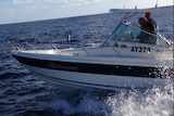 Motor boat being driven on the ocean with two men aboard