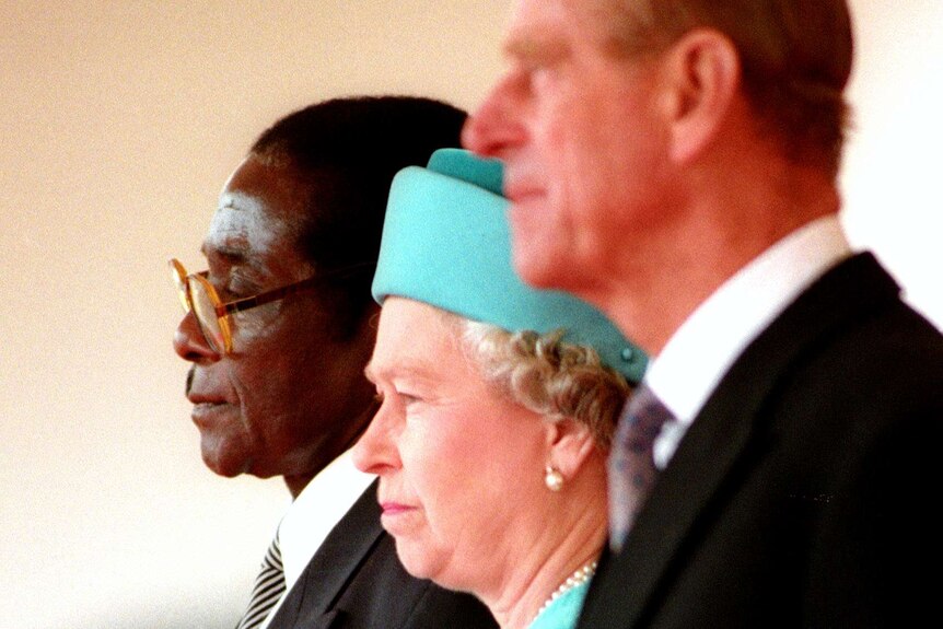 Mugabe stands alongside Queen Elizabeth the II and the Duke of Edinburgh