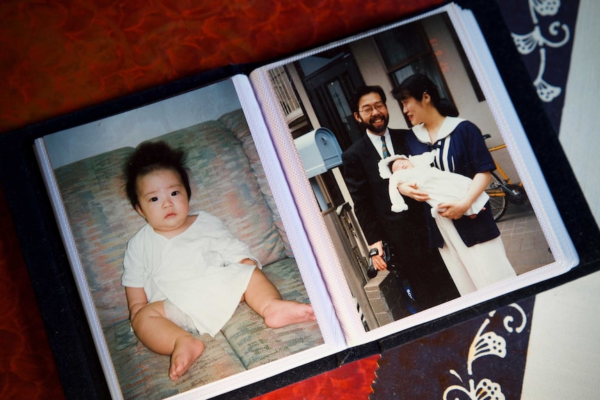 A photo album featuring a picture of a baby and a couple holding a baby together