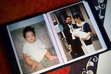 A photo album featuring a picture of a baby and a couple holding a baby together