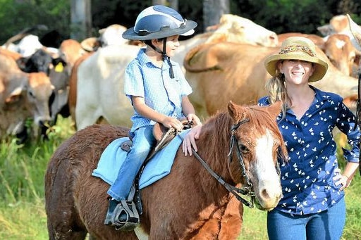 Karen Jarling with her son Hamish riding a horse with cattle in the background.