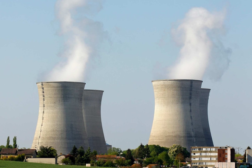 Four nuclear cooling towers, emitting steam.