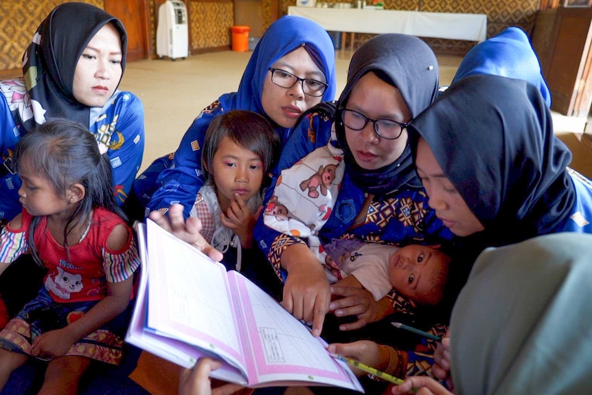 A group of women crowd around a chart