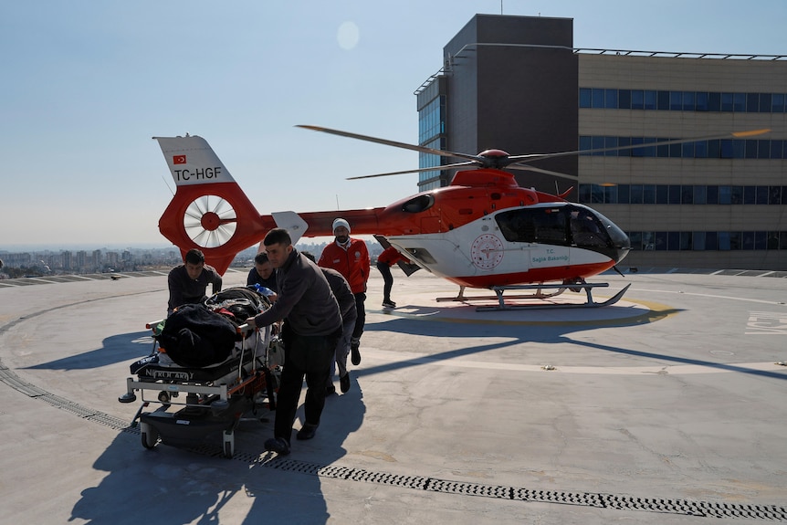A patient on a trolley is wheeled away from a Turkish helicopter.