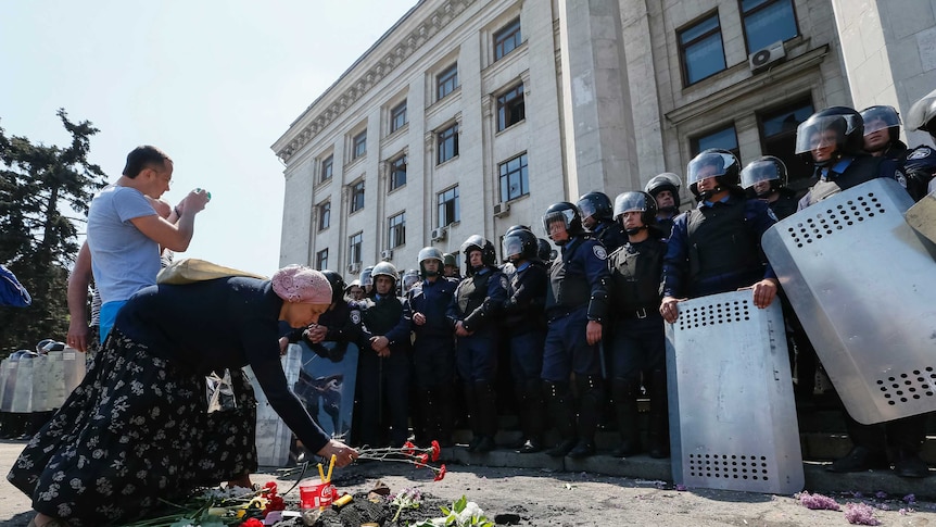 A woman lays flowers outside a trade union building where people died in a fire in Odessa.
