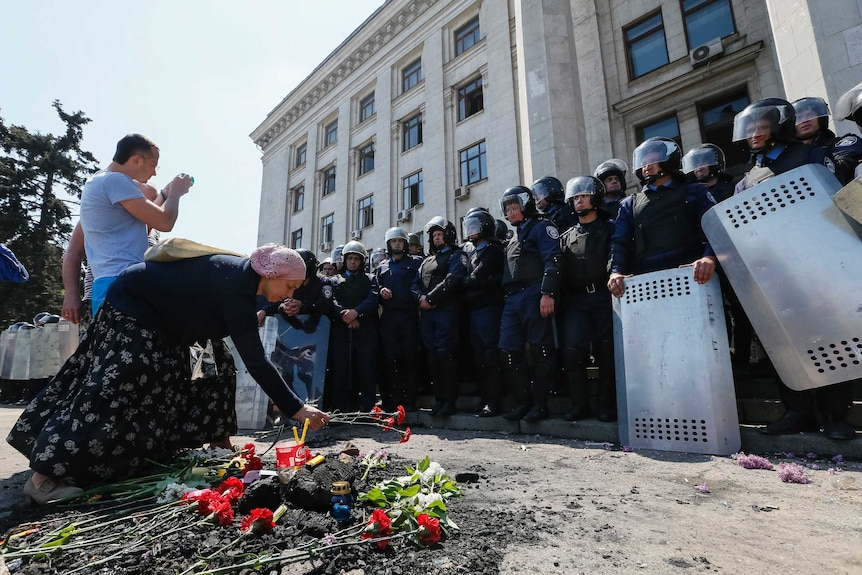 Woman lays flowers outside trade union building in Odessa