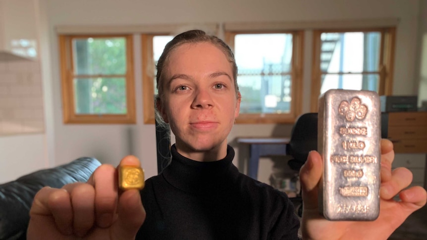 Woman holding a gold block and silver bar