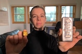 Woman holding a gold block and silver bar
