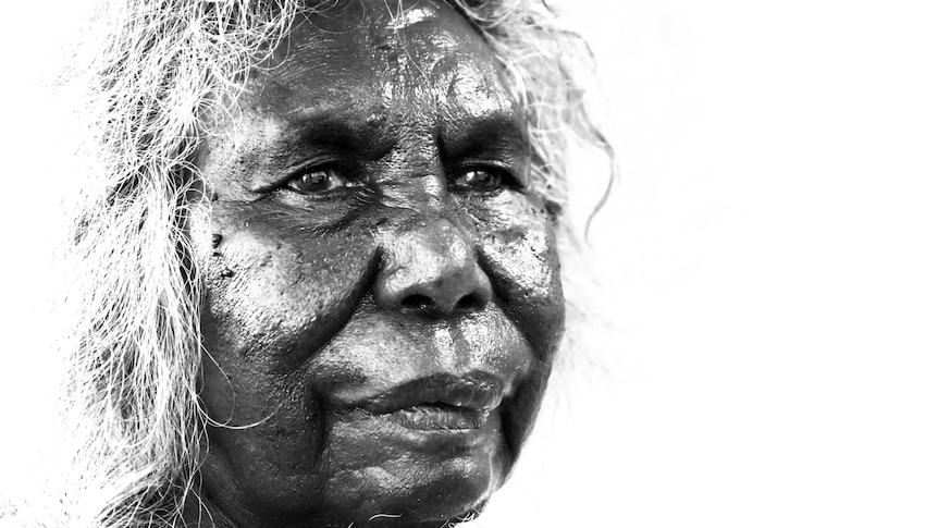 A black and white portrait of an older Kaiadilt woman in profile. She has dark skin and white, curly hair.