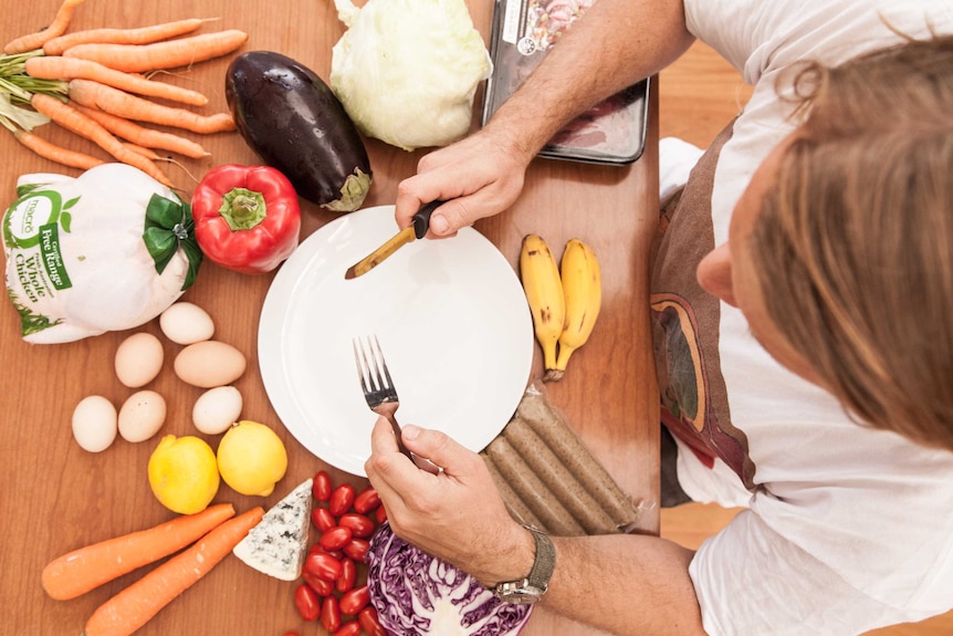 A person with an empty plate surrounded by meat and vegetables.