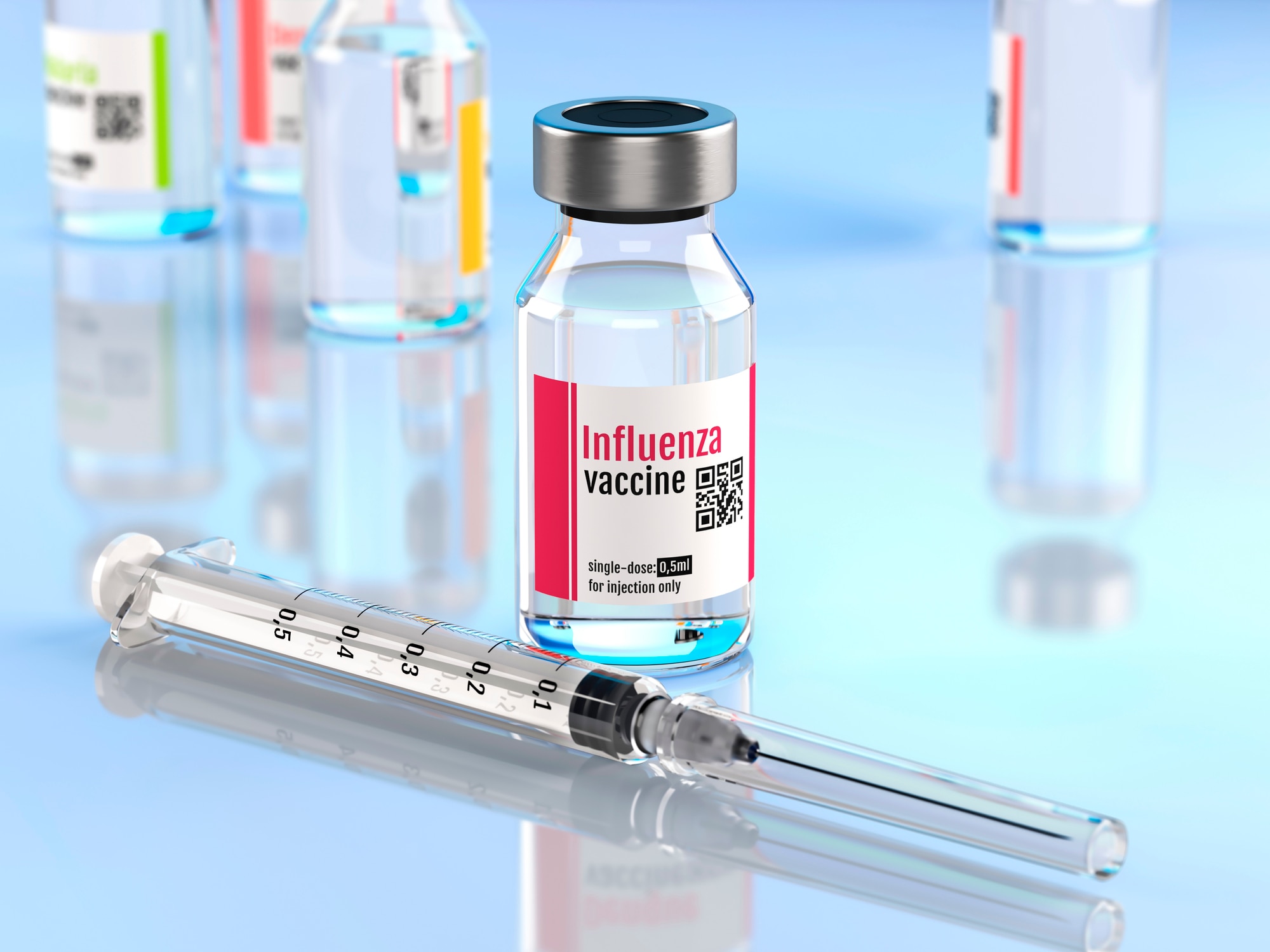 Close up of a influenza vaccine vial and needle with other vials in background.