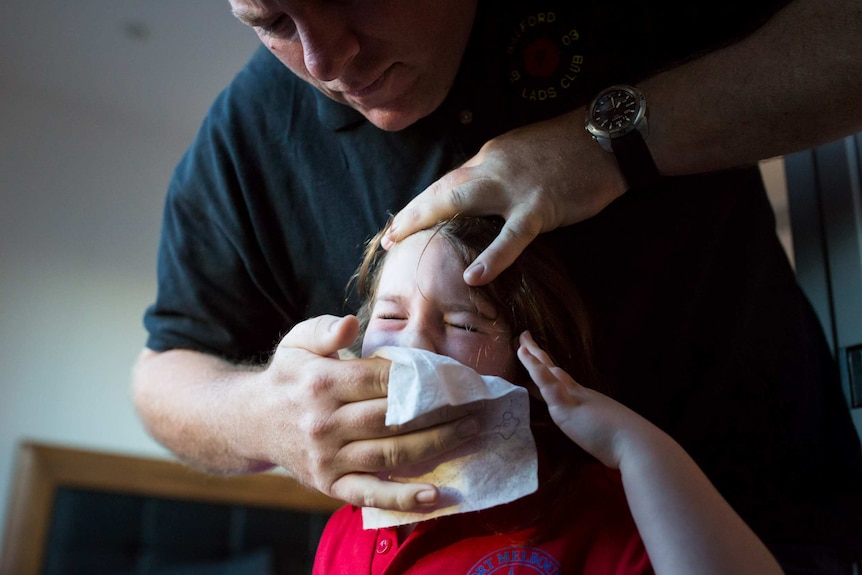 Rodney McMurtrie wipes his daughter's nose.