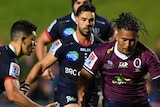 A Melbourne Rebels player and a Queensland Reds opponent run towards the ball in a Super Rugby AU match in Sydney.
