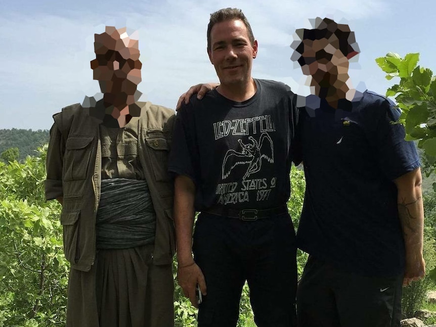Jamie Bright poses with two Kurdish militiamen