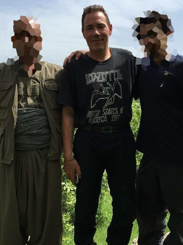 Jamie Bright poses with two Kurdish militiamen
