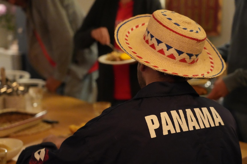 A man in a navy blue shirt with Panama on the back sits at a dining table.