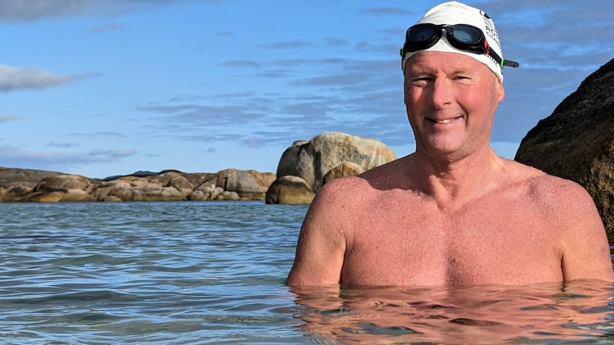 A man in goggle chest deep in ocean