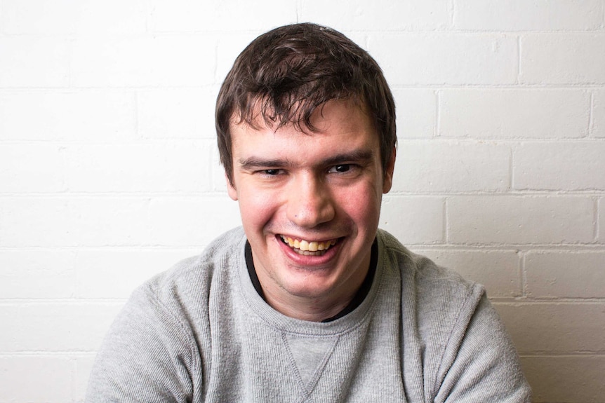 Sean Cook sits in front of a white wall.