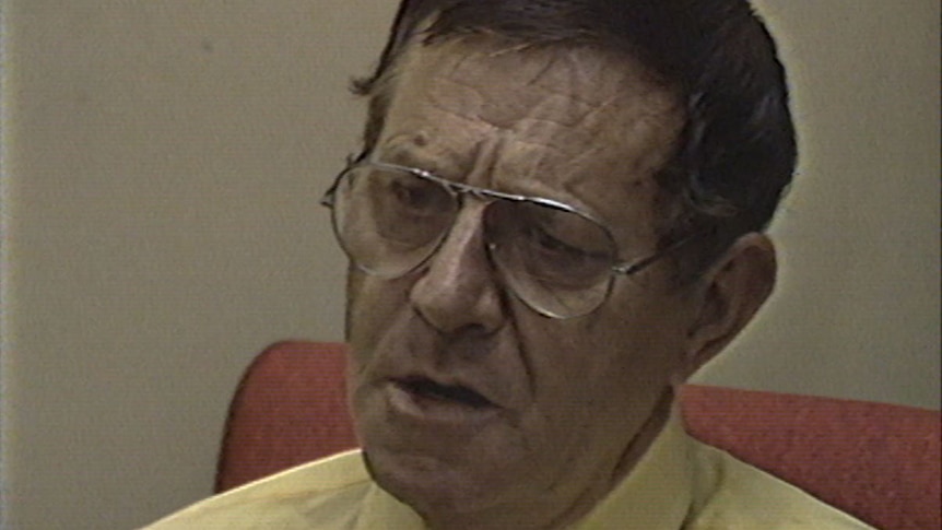 A middle-aged man wearing glasses is interviewed for television.
